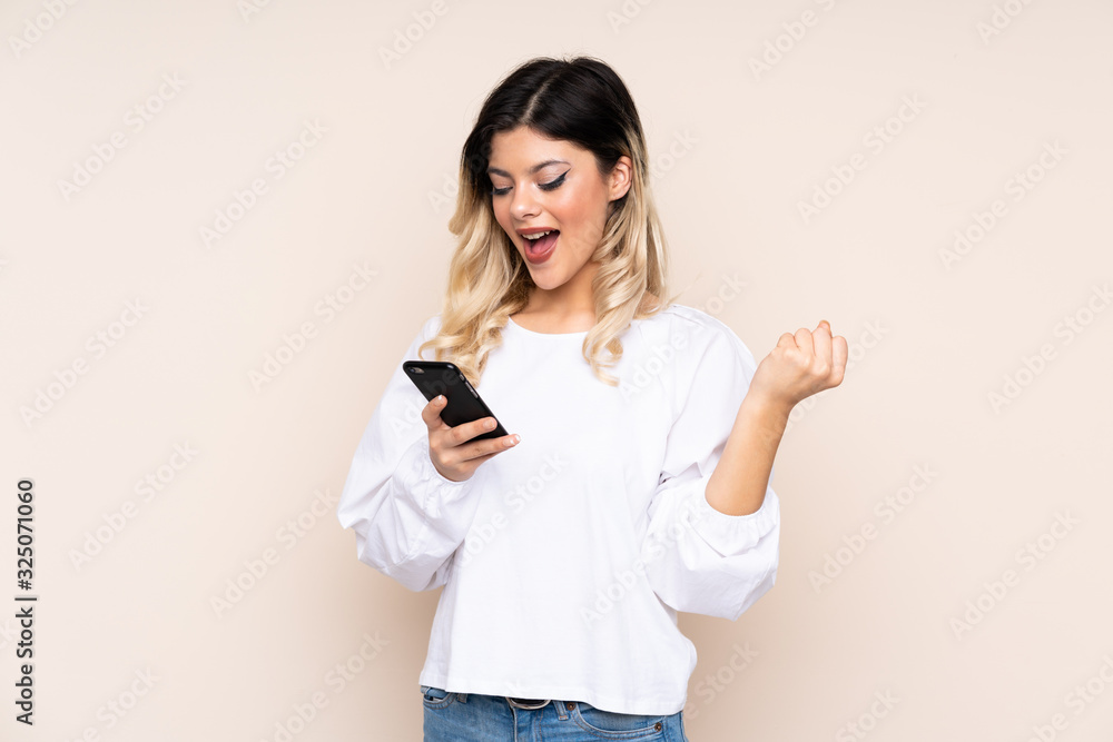 Teenager girl isolated on beige background surprised and sending a message Teenager girl isolated on beige background surprised and sending a message