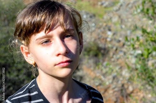 A Small girl front face, She has long hair with a fringe and gold earrings during a walk in the beautiful countryside in Benahavis  photo