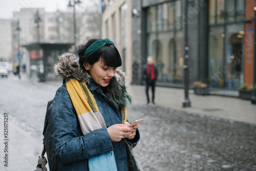 Stylish woman using smartphone in the street