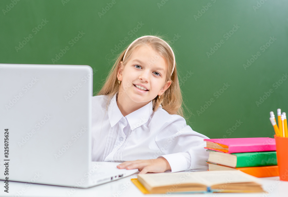 Smiling young gurl uses laptop in a school Smiling young gurl uses laptop in a school