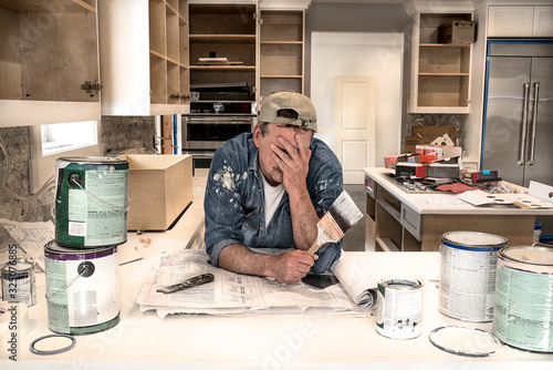 Exhausted, tired painter, face in hands holding wet paint brush in messy home kitchen fixer upper remodel, dripping paint cans, PREVIOUSLY SUBMITTED & ACCEPTED, TOP SELLER