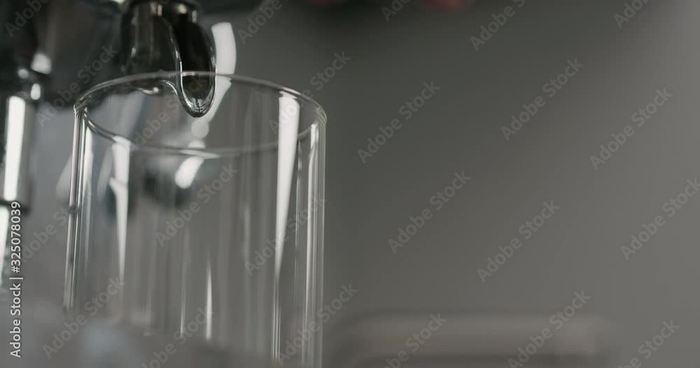 Slow motion low angle water pour from coffee machine into glass Slow motion low angle water pour from coffee machine into glass