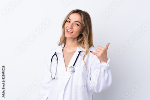 Young woman over isolated white background wearing a doctor gown and making phone gesture