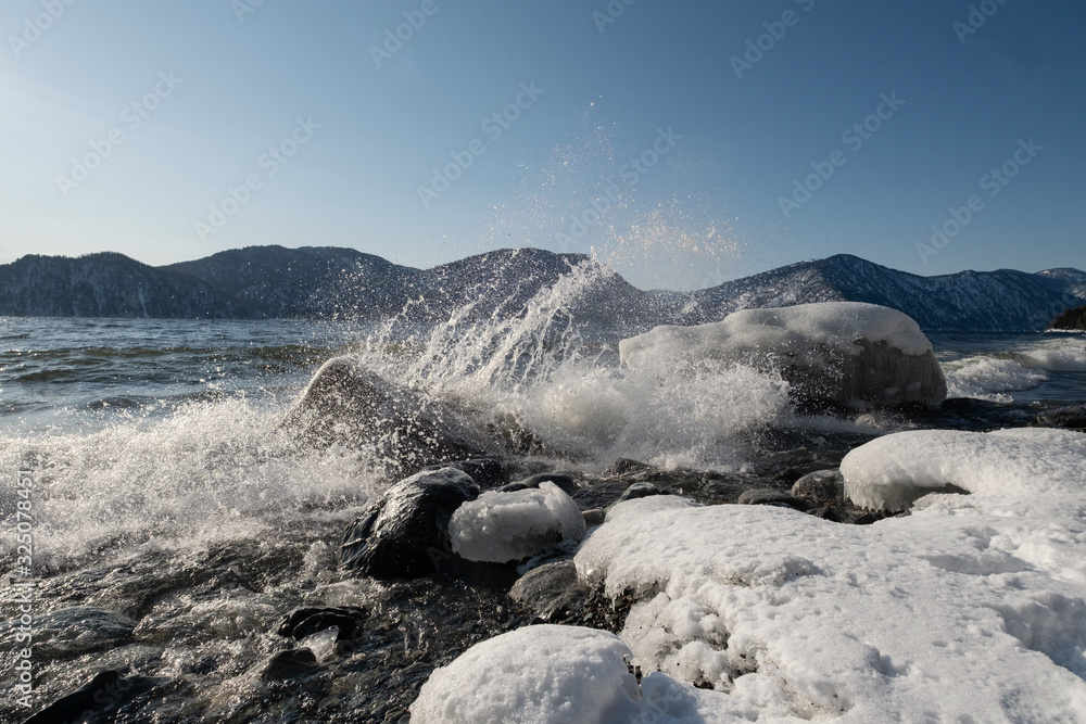 Splashing waves in ice water. Winter mountain lake landscape Splashing waves in ice water. Winter mountain lake landscape