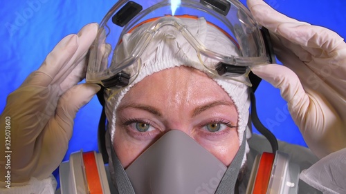 Scientist virologist in respirator. Slow motion. Woman close up look wearing protective medical mask. Concept health safety N1H1 virus protection coronavirus epidemic 2019 nCoV. Chroma key blue film. photo