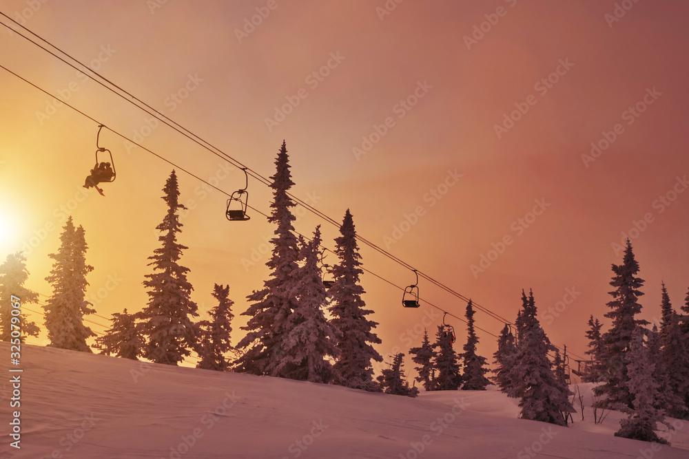 Obraz premium Ski lift in snowfall in mountains ski resort Sheregesh, Russia White winter sunset view landscape with chairlifts and snow covered fir tree forest