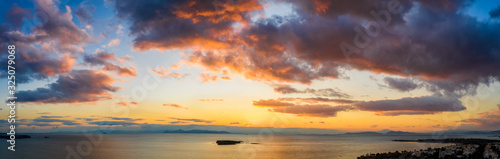 Fototapeta Weites Aerial Panorama eines bewölkten Sonnenunterganges über dem Meer mit von der Sonne rot angestrahlten Wolken