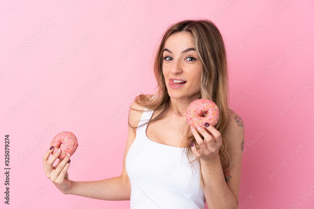 Young woman over isolated pink background holding a donut Young woman over isolated pink background holding a donut