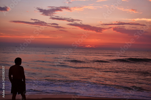 a man watching a colorful sunset in the beach of goa © SUBHAJIT