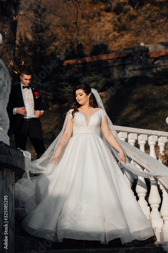 Wedding in a beautiful location. Wedding couple, bride and groom posing on the stairs. Elegant wedding dress. Bride, fashion model jewelry and beauty face, gorgeous female