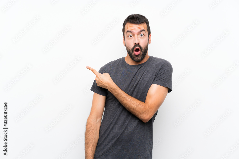 Young handsome man over isolated white background surprised and pointing side Young handsome man over isolated white background surprised and pointing side