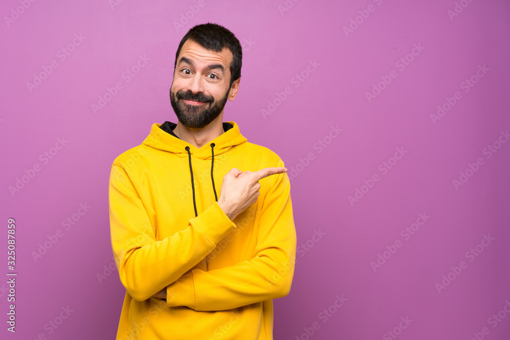 Handsome man with yellow sweatshirt pointing finger to the side Handsome man with yellow sweatshirt pointing finger to the side