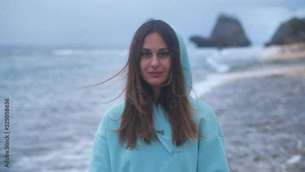Portrait hipster woman in a turquoise sweatshirt at ocean background in twilight. 4k Portrait hipster woman in a turquoise sweatshirt at ocean background in twilight. 4k
