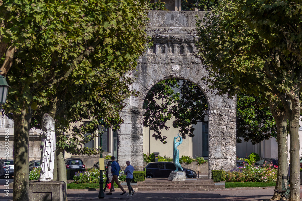 Ancient arch and modern blue sculpture in the historic center of Aix-les-Bains, France