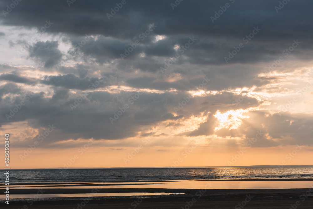 Dramatic scenic landscape above the sea. The sun rays break through the clouds. Gentle tones of the scenery. Travel and vacation concept. Saint Petersburg, Russia. Beauty world. Orange tones of sky.