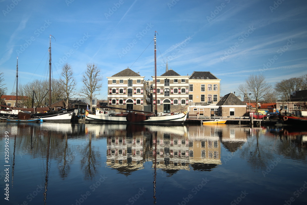 Old ancient warehouses and ships are reflecting on the Turfsingel of the town Gouda