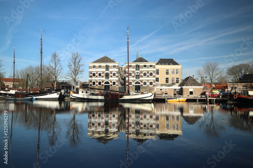 Old ancient warehouses and ships are reflecting on the Turfsingel of the town Gouda