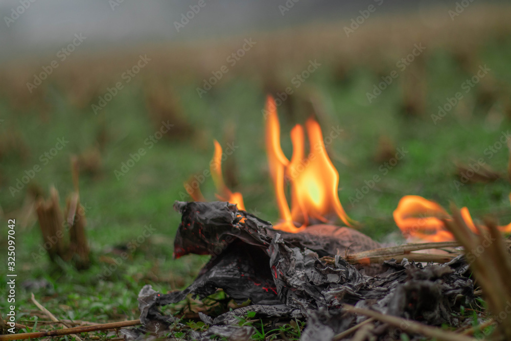 Newspaper is burning with fire in a field over green blurry background Newspaper is burning with fire in a field over green blurry background