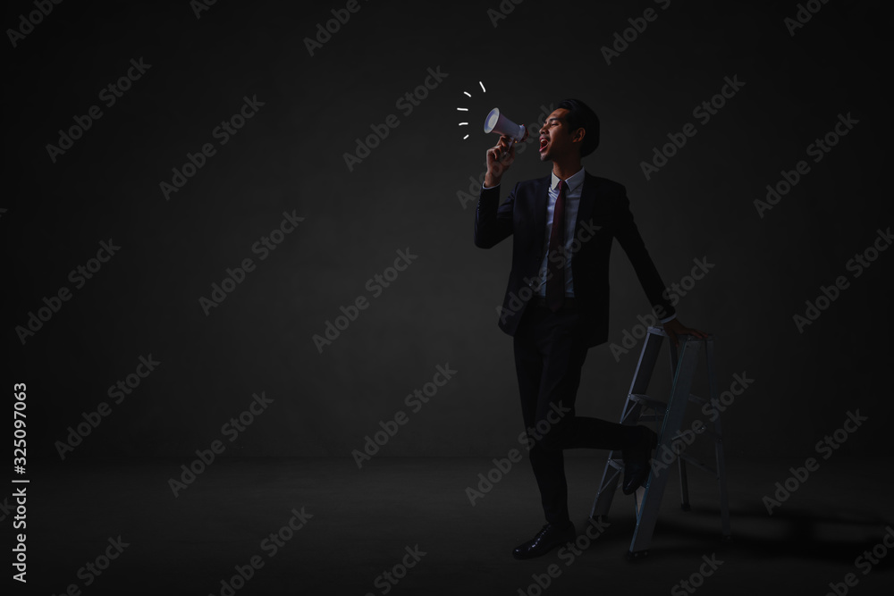 Fototapeta premium businessman standing and announce with megaphone to public relations in dark room