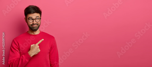 Foto Curious unshaven man with cheerful smile, introduces new interesting promo, poin