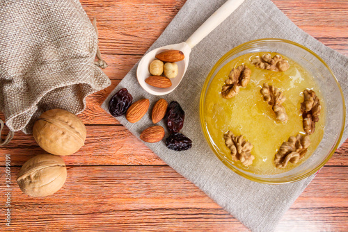 Delicious food for a snack and health. On a linen bowl with a bowl of honey and walnuts  a woven bag with nuts in the shell.