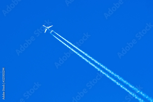 Plane flying in the blue sky amid clouds and sunlight, travel by air