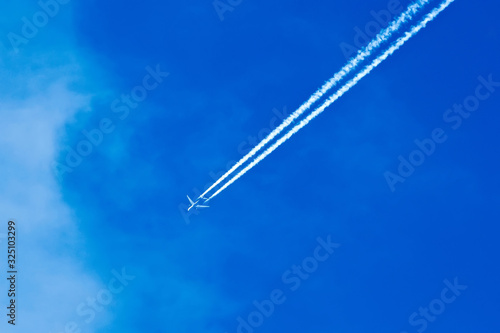 Plane flying in the blue sky amid clouds and sunlight, travel by air