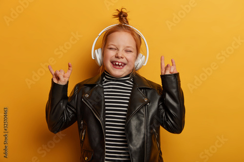 Valokuvatapetti Happy small child rocker makes horn hand sign, rock n roll gesture, enjoys favou