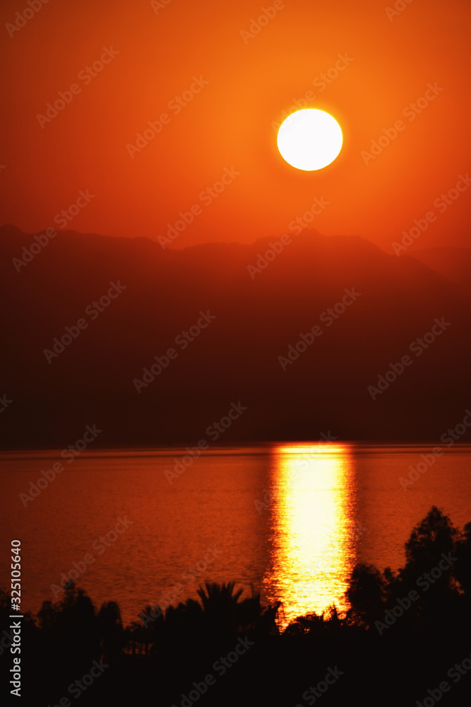 the setting sun over the mountains which is reflected from the water