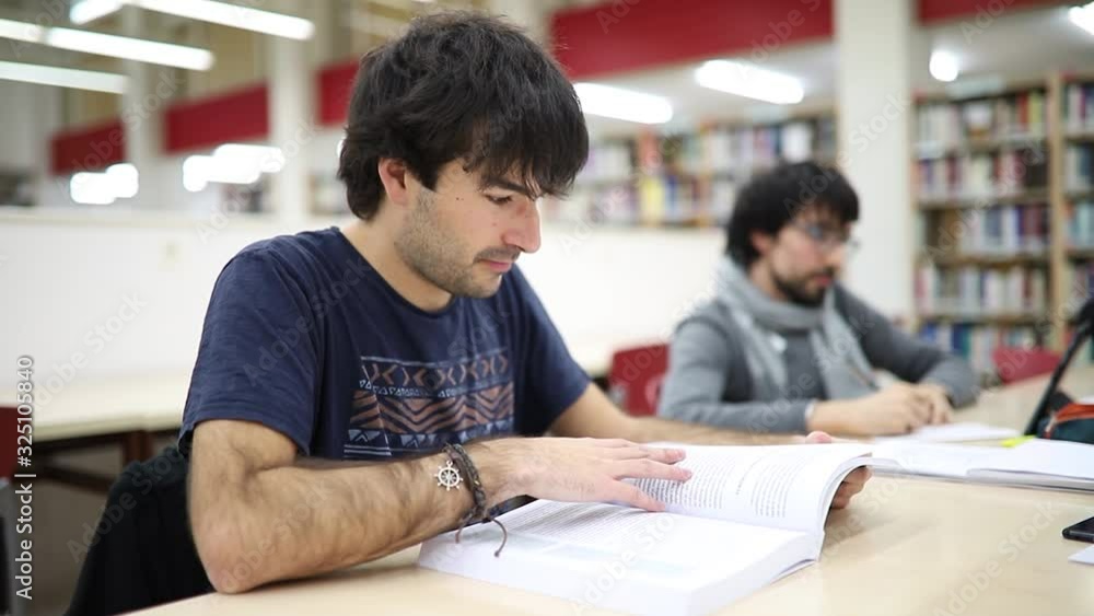 young adult studying in the university library, focused on his book. slow motion young adult studying in the university library, focused on his book. slow motion