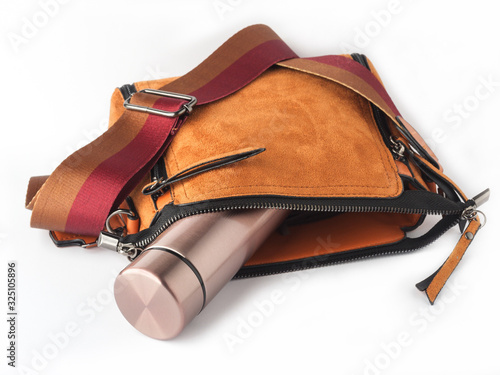 Woman's bag with metallic water bottle isolated on white background.