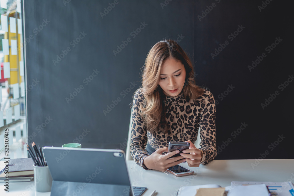 Young asian beautiful woman using smartphone sitting at her working place in office. Young asian beautiful woman using smartphone sitting at her working place in office.