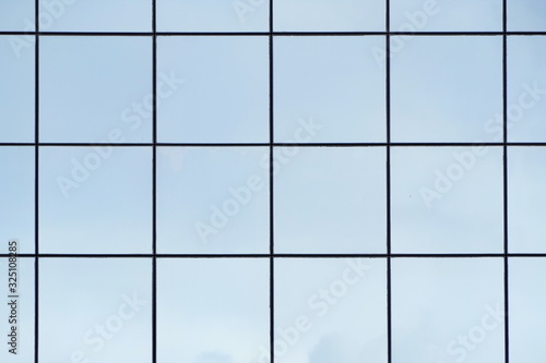 Glass with mirror effect in frames, facing of modern office building. Reflection of the sky in the glass facade of an office building