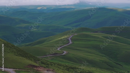 Empty serpentine road, Dzhily Su asphalt dangerous beautiful winding freeway in caucasus mountains at summer sunny sunset - Aerial drone view photo