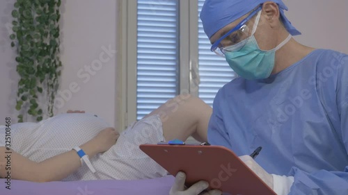 A doctor prepares a young pregnant woman for labor in the hospital. Surgeon gynecologist in rubber gloves prepare to examine pregnant woman lying on operating table. photo