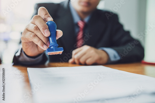Businessman stamping with approved stamp on document contract.