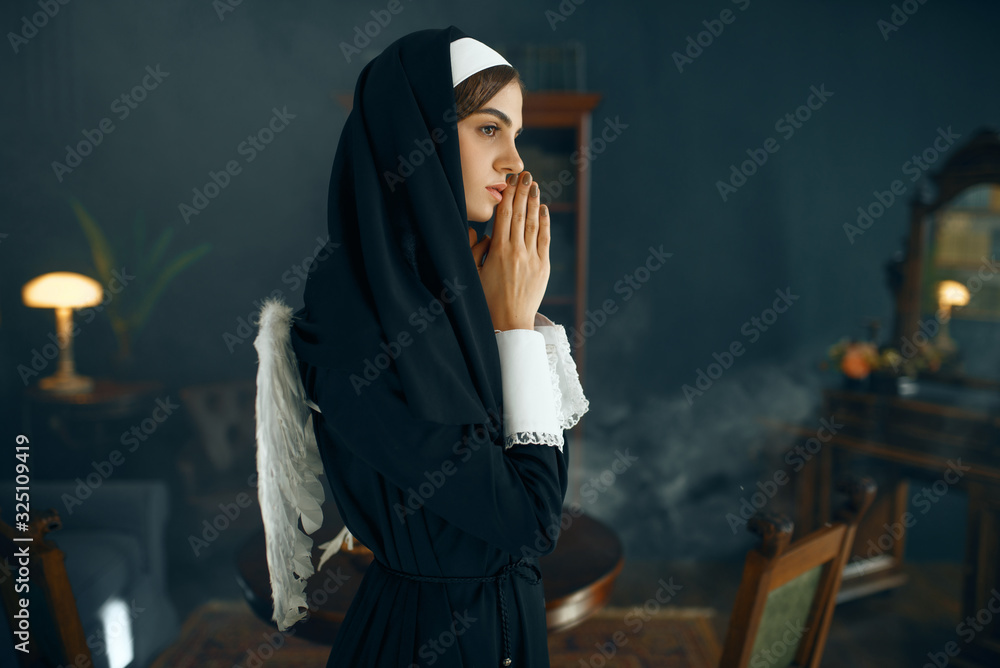 Young nun in a cassock prays crossed her arms Young nun in a cassock prays crossed her arms