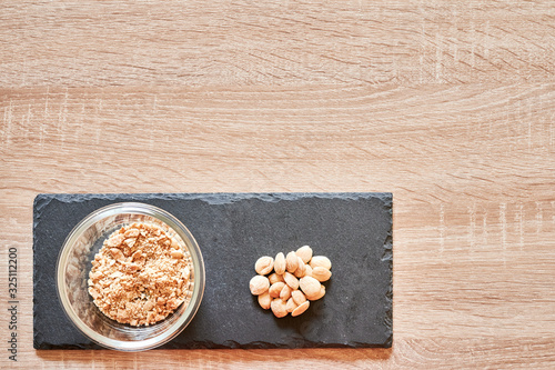 top view of whole almonds and a bowl of ground almonds on a slate board over a wooden table