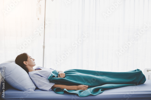 Patient person sleep on patient bed in hospital room. Sick woman get high fever. Illness girl get Surveillance or monitoring symtoms in separate patient room. She get tired, weak. Patient stay alone