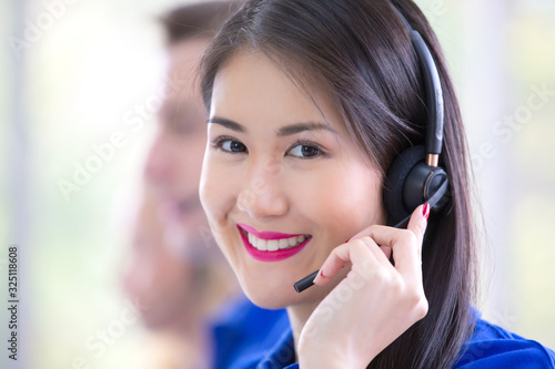 Smiling female customer support operator with headset working in office