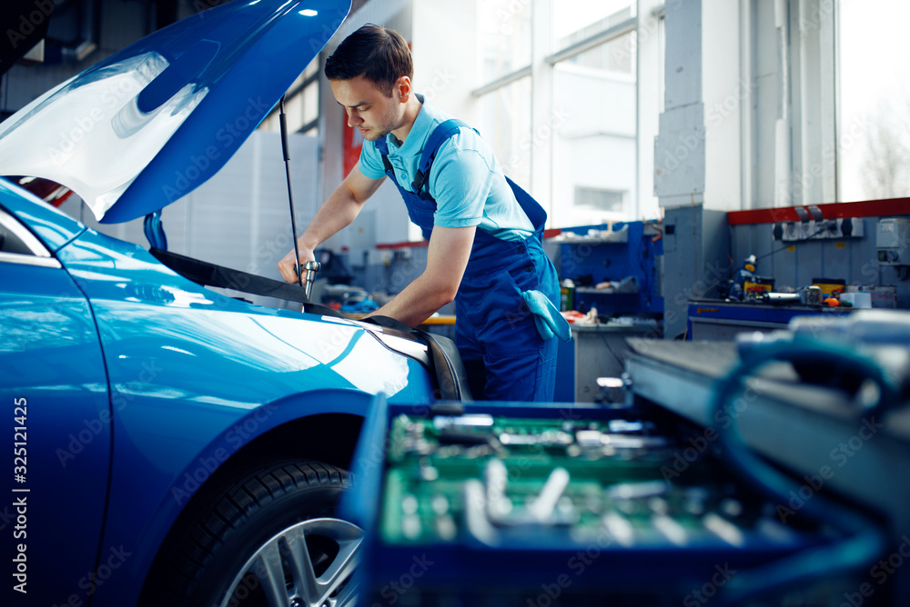 Worker in uniform checks engine, car service Worker in uniform checks engine, car service