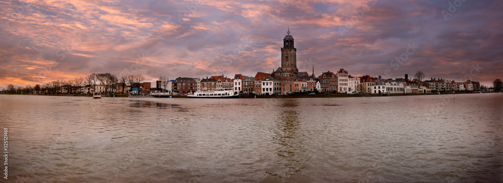 Panorama photo taken in winter of the Hanseatic city of Deventer on the other side of the river IJssel, with beautiful colored cloudy skies