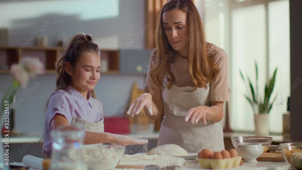 mother and daughter clapping hand on flour at kitchen in slow motion mother and daughter clapping hand on flour at kitchen in slow motion