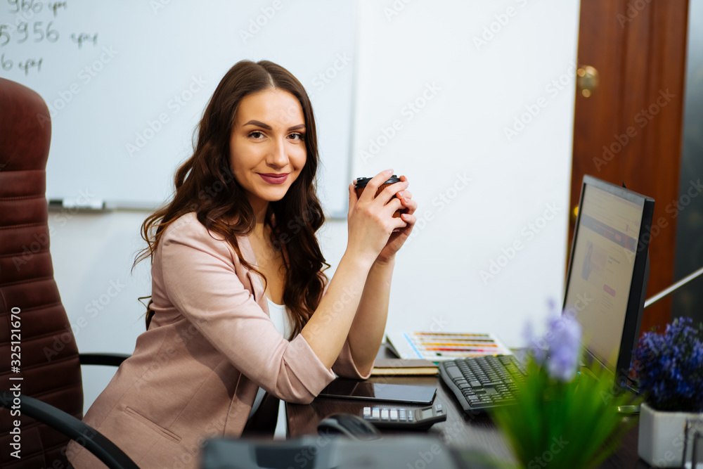 beautiful business brown-haired lady with long hair sitting at the desk on an office chair looking forward beautiful business brown-haired lady with long hair sitting at the desk on an office chair looking forward