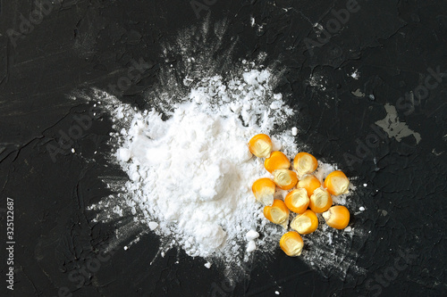 Corn starch with yellow grains on a black background, top view. Corn white starch and yellow kernels on the table. Starch and corn grains on a black background, top view.