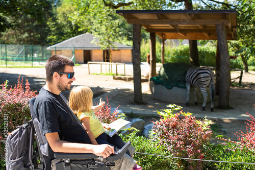 Принти на полотні Disabled Father in Wheelchair enjoying Nature with Daughter Girl in Outside zoo park on a sunny day