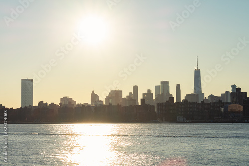 Lower Manhattan Skyline on the East River in New York City with a Bright Sun Before Sunset