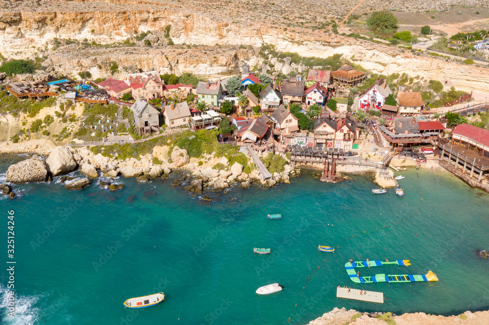 Aerial view of tourist attraction Popeye village, also known as Sweethaven village. Sunny day, blue sea. Mellieha city. Malta