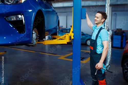 Foto Repairman lifts vehicle on car service station