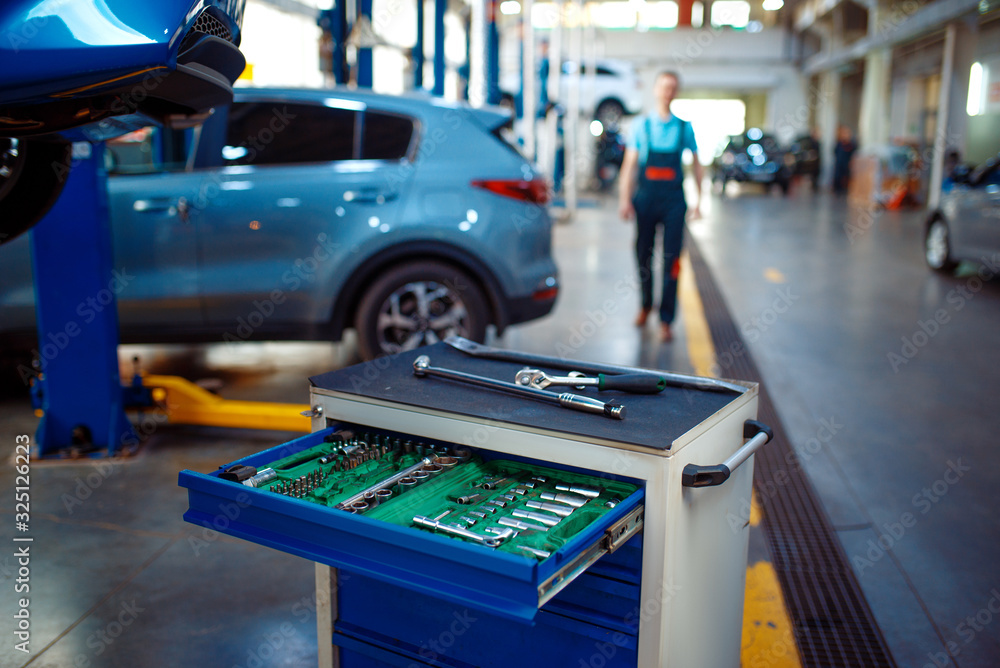 Toolbox, worker at vehicles on lifts on background